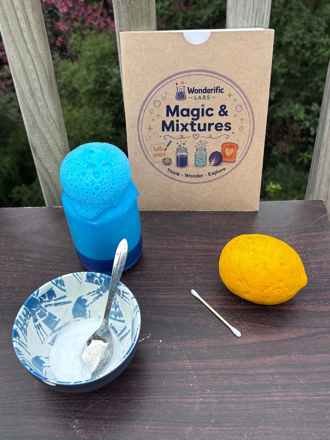 The Magic and Mixtures pack beside a foaming blue jar, a bowl of baking soda and a lemon