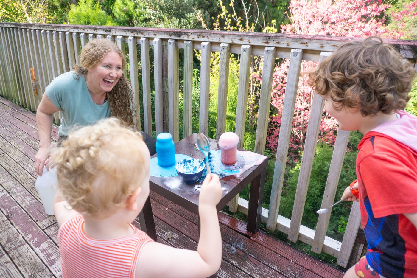 Dani laughing with two children around a table of fizzing jars on the deck